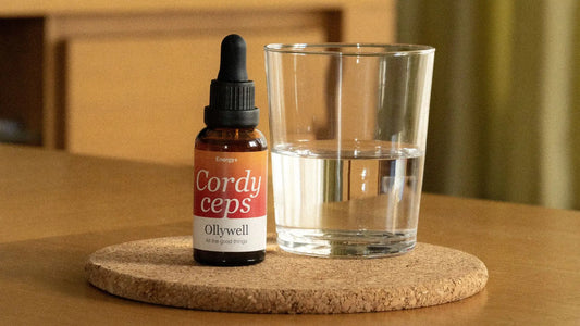 On the table is a glass of water and liquid Cordycep extract from Ollywell.